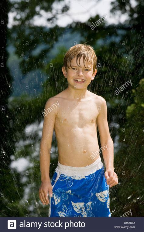 Young blonde teen playing with mature blonde. A young boy standing in a sprinkler Stock Photo - Alamy