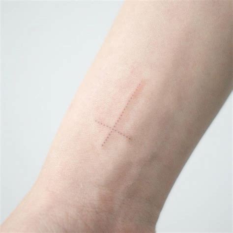 Cross tattoo on the wrist. Small dotwork Christian cross tattoo on the right inner