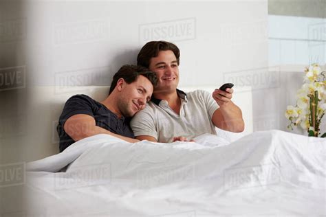 Male Gay Couple Relax In Bed Together Watching Tv Stock Photo Dissolve