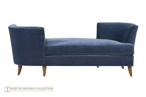 A gray tete a tete settee draped in a dark blue fringe throw blanket and matched with a gold accent table sits in front of a white bar cabinet. Lynae Tete a Tete | Designer Tete a Tete By Kristin Drohan