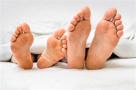 Keine kalten füsse unter der bettdecke. Füße von ein paar im Bett unter der Decke — Stockfoto ...