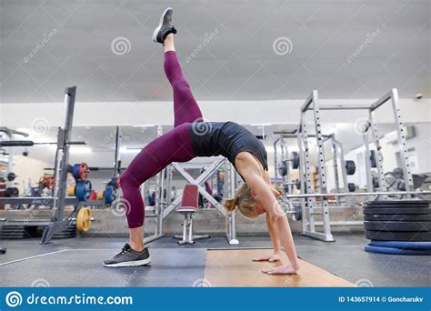 Attractive blonde sportswoman doing stretching exercise standing feet wide apart leaning forward resting on body bar in. Adult Sporty Blonde Woman Stretching Body While Doing Yoga ...