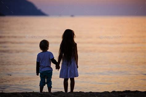 Use them in commercial designs under lifetime, perpetual & worldwide rights. Young boy and girl holding hands while standing on beach ...
