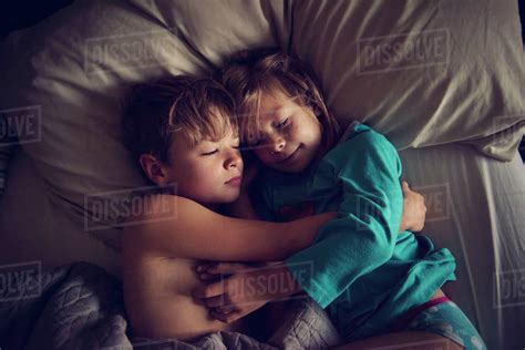 Overhead view of loving siblings sleeping together on bed at home ...