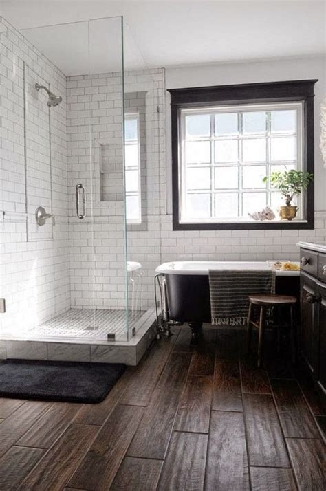 Classic white subway tile will always add timeless appeal to any bathroom. wood tile floor, white subway tile with dark grout, black ...