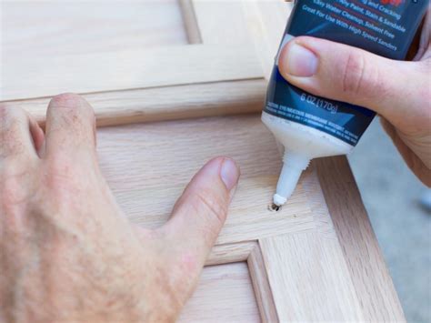 Drilling the old rivets out of the broken hinge. How to Refinish Cabinets Like a Pro | HGTV