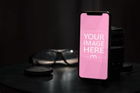 Download Online mockup featuring a space gray iPhone standing on a desk in a dark room and leaning on a ...