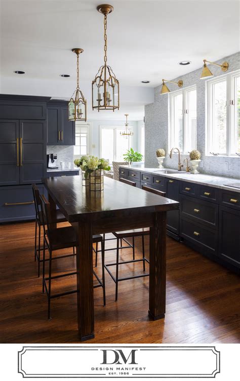 Dark natural wood cabinetry and island support dark marble countertops over grey stone flooring. charcoal gray kitchen- Wood Island- Brass fixtures Hardware via design manifest. Dark Gray- BM ...